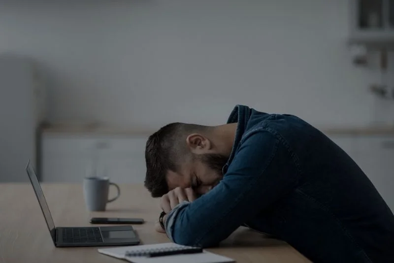 a-person-is-sleeping-on-a-table-in-front-of-a-laptop
