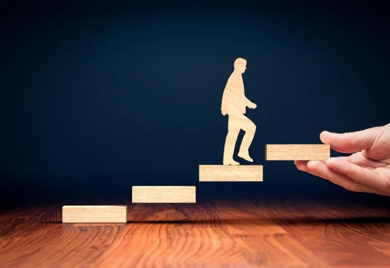 a hand is holding a wooden figure of a person walking up a staircase